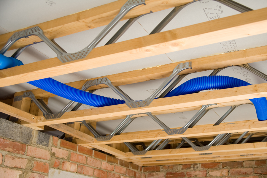 Blue MVHR ducting running through open web spaces of Posi-Joists on site